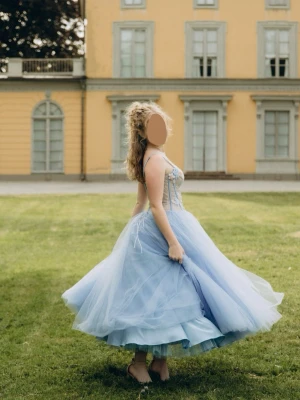 Balklänning - Säljer min balklänning 💙 Använd endast en gång. Klänningen är specialdesignad av designern KICHKAR. Den har snörning i ryggen (korsett) och en extra underkjol för extra volym. Dessutom ingår en matchande blå väska.