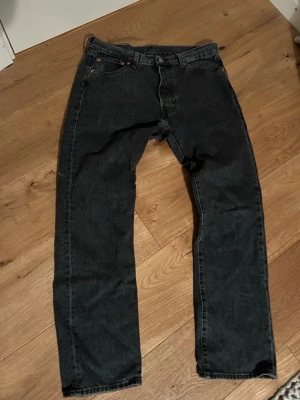 Levis 501 - Ett par svart/grå Levis 501 i väldigt fint skick som jag endast använt ett fåtal gånger då dom inte riktigt passade mig. Jeansen är i storlek W34 och L30 men jag skulle säga att dem mer sitter som W32. Skriv om du har några frågor!