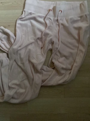 Ljusrosa mjukisbyxor med dragsko - Säljer ett par ljusrosa mjukisbyxor med bred resår i midjan och matchande dragsko. Byxorna är tillverkade i ett mjukt och skönt material, perfekta för chill dagar. Klassisk passform och raka ben.