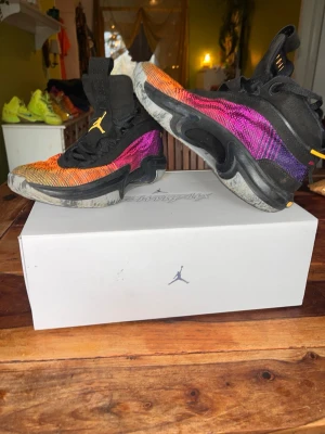Jordan XXXVI Deadly Pink sneakers - Säljer ett par Jordan XXXVI Deadly Pink sneakers med cool färggradient från orange till rosa och lila. Skorna har svart mesh-överdel, högt skaft och Jumpman-logga i gult på tungan. Perfekta för basket för skorna väger nästan inget eller om du inte kör basket så är dem jätte snygga så man kan använda dem i streetstyle, tillverkade i syntetmaterial och mesh för bra ventilation.