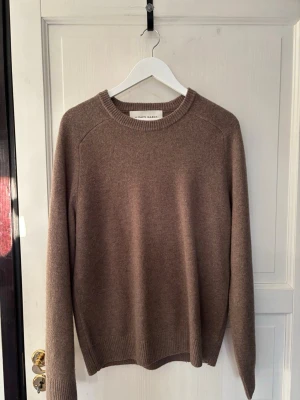 A DAY’S MARCH | Strl. M - Säljer en enkel och stilren brun stickad tröja från A DAY’S MARCH. Tröjan har rund halsringning, långa ärmar och ribbade muddar vid ärmslut  och nederkant. Perfekt för lager på lager och passar till det mesta.