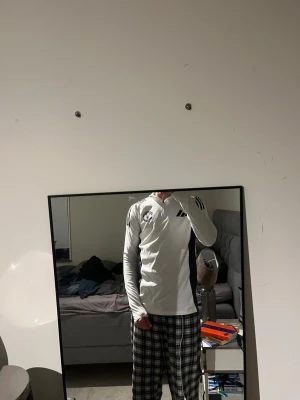 Manchester United träningströja - Säljer en vit långärmad träningströja från Adidas med Manchester United FC-logga på bröstet. Tröjan har svarta detaljer, dragkedja vid halsen och tre svarta ränder på axlarna. Perfekt för fotbollsträning eller gymmet. Använd endast enstaka gånger 