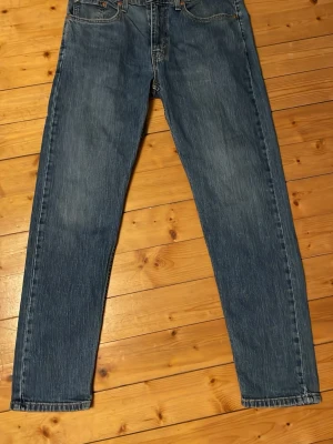 Blå raka jeans från Levi's - Klassiska blå jeans från Levi's med rak passform och fem fickor. Jeansen har en tidlös tvätt och är tillverkade i slitstark denim. Perfekta för en avslappnad och stilren look. Levi's-logga syns på bakfickan. Modell 502 w32,L32 skulle säga att de sitter mer som 30-31w hör av er vid frågor eller funderingar priset går att diskutera!