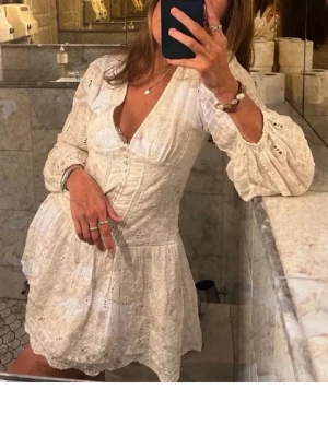 Vit klänning - Superfin vit kortklänning med v-ringning och mönstrade detaljer. Perfekt till studenten eller bara en sommardag! Har en liten deofläck i ena armhålan men som knappt syns (se sista bilden). Annars i fint skick