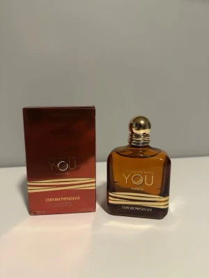 Stronger With You Amber parfym - Stronger With You Amber från Emporio Armani är en exklusiv parfym i en elegant, bärnstensfärgad glasflaska med gulddetaljer och rund guldfärgad kork. Förpackningen är matchande i brons och guld. Doften är varm och lyxig, perfekt för dig som gillar unika och sofistikerade parfymer.