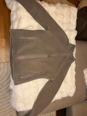 Beige fleecejacka med dragkedja - Mysig beige fleecejacka med hög krage och hel dragkedja framtill. Två praktiska fickor med dragkedja på framsidan. Perfekt för lager-på-lager och håller dig varm under kyliga dagar. Enkel och stilren design som passar till det mesta. Jag har en svart lika dan också om någon är intresserad 