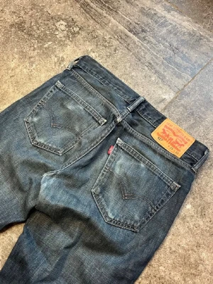 Levi's 527 bootcut jeans blå denim vintage - Säljer ett par klassiska Levi's 527 bootcut jeans i blå tvättad denim. Jeansen har fem fickor, läderpatch bak och den ikoniska röda Levi's-taggen. Perfekt passform med något utsvängda ben och snygga slitningar för en avslappnad look.