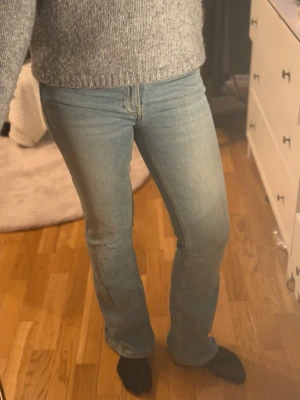 Ljusblå bootcut jeans - Säljer ett par ljusblå bootcut jeans med klassisk femficksdesign och normal midja. Jeansen har en snygg tvättad look och är tillverkade i ett mjukt denimtyg som sitter skönt. Perfekta för en avslappnad och trendig stil.