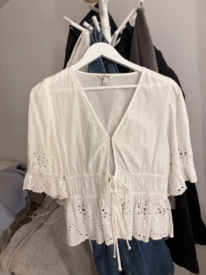 Vit blus med broderi från Aware - Storlek L men passar på mig som vanligtvis bär storlek S. Söt vit blus från Aware med broderade detaljer och knytband i midjan, nyskick