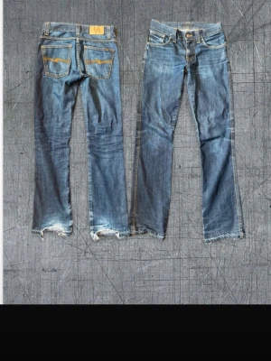 Blå slim jeans från Nudie Jeans - Säljer ett par klassiska blå slim fit jeans från Nudie Jeans. Jeansen har snygga slitningar, orange sömmar och detaljerade bakfickor. Tillverkade i 100% bomull för en skön känsla och tidlös look. Perfekta för dig som gillar en avslappnad men ändå stilren vibe. Redan snygga fades men byggs såklart på med tiden. Pris är diskuterbart så fråga om er är något du undrar över