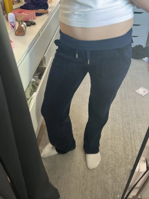 Marinblå Juicy Couture byxor - Säljer ett par mörkblå Juicy Couture byxor i storlek xxs med bred resår i midjan. De är jättesköna och snygga. Perfekta för chill dagar och riktigt sköna att ha på sig. De silvriga på byxorna har rostat pyttelite men inget som syns på. (Villig att sänka pris)