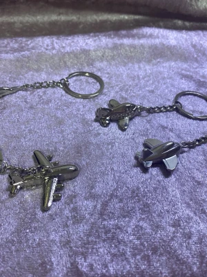 Nyckelring med flygplanshänge i metall - Säljer en cool nyckelring med ett detaljerat flygplanshänge i silverfärgad metall. Perfekt att hänga på väskan eller använda till nycklarna för en unik touch. Kedjan och ringen är också i metall och ger en stilren look. 55kr/st , helt ny 