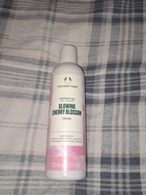 The Body Shop Glowing Cherry Blossom - Duschtvål från The Body Shop i doften Glowing Cherry Blossom. Vegansk formula med noter av japansk körsbärsblom, osmanthus och sandelträ. Flaskan är vit och rosa och rymmer 250 ml. Perfekt för dig som vill ha en fräsch och blommig duschupplevelse.