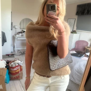 Beige ärmlös stickad tröja - Säljer en beige, ärmlös stickad tröja med lös passform och bred halsringning. Båtringring och nervikbar i halsen. 