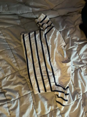 Randig vit och marinblå tröja - Snygg vit tröja med marinblå horisontella ränder och rund hals. Tröjan har långa ärmar och är tillverkad i ett mjukt, tunt material som passar perfekt till jeans eller kjol. Enkel och klassisk design som aldrig går ur tiden.