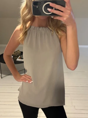 Topp/Blus - Stilren beige/grå topp eller blus med rak passform och hög halsringning. Toppen är ärmlös och har en enkel, clean look. Superfint skick, men kommer tyvärr inte till användning💞