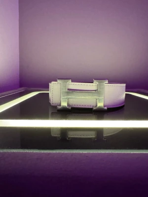 Vitt skärp med metallspänne - Snyggt vitt skärp med ett stort, stilrent metallspänne i silverfärg. Skärpet har en clean look och passar perfekt till jeans eller byxor för att lyfta din outfit. Tillverkat i slätt skinn för en exklusiv känsla.