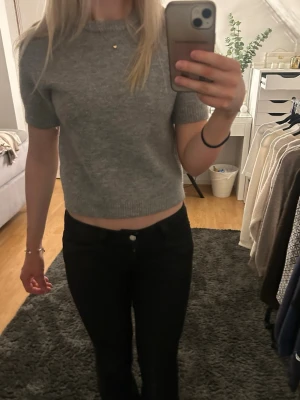 Grå kortärmad stickad tröja - Säljer en enkel och stilren grå stickad tröja med korta ärmar och rund hals. Endast använd en gång. 