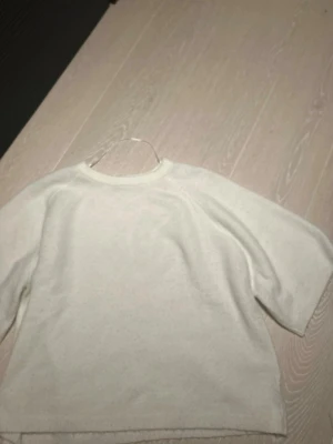 Vit stickad tröja med rund hals - Mysig vit stickad tröja med rund hals och raka ärmar. Tröjan har en enkel och stilren design som passar perfekt till många olika outfits. Materialet ser mjukt och bekvämt ut, perfekt för kyligare dagar.