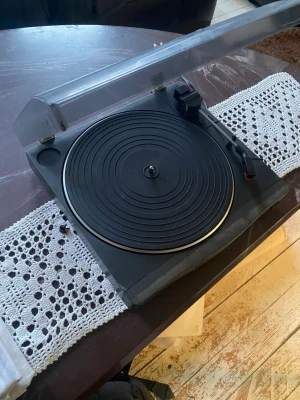Svart vinylspelare  - Säljer en klassisk svart LPspelare med rund tallrik och genomskinligt lock. Spelaren har en enkel och stilren design med tonarm och pickup. Perfekt för dig som vill lyssna på LP-skivor och ge din musik en retro känsla.