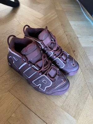 Nike Air More Uptempo bruna sneakers - Priset går att diskutera. Nypris vid köp $180 använda 6-7 gånger. Bruna Nike Air More Uptempo sneakers med stora AIR-bokstäver på sidorna. Skorna har en chunky sula med synliga luftbubblor och detaljer i vitt runt bokstäverna. Tillverkade i läder och textil med matchande bruna skosnören och broderad Swoosh på tån.