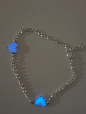 Självlysande silverarmband med hjärtberlocker  - Snyggt silverfärgat armband med två hjärtformade berlocker. Hjärtana har en cool effekt och lyser blått i mörker. Kedjan har rundade länkar och ett smidigt lås. Perfekt accessoar för dig som gillar unika detaljer och vill sticka ut lite extra. Material: Rostfritt stål. Kedjans längd ca 20 cm, vill man ha en annan längd så kan du bara skriva till mig så ordnar jag det 💖 