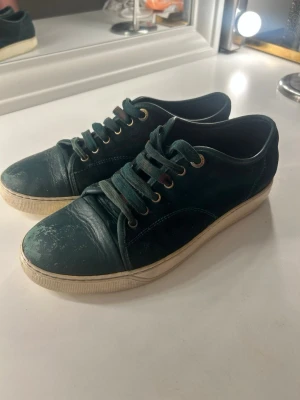 Lanvin toe cap - Säljer Lanvin sneakers i mörkgrön färg – stilrena och perfekta inför sommaren.  Skick: Använda med visst slitage. Mindre färgbortfall på toe cap samt färg på skosnören (se bilder). I övrigt fullt funktionella.  Ingår även i paketet: - Raw jeans   - Acne Studios jeans (nypris ca 2 500 kr)   - Levi’s jeans   - G-Star jeans   - Peak Performance väst    Vid frågor är det bara att höra av sig!