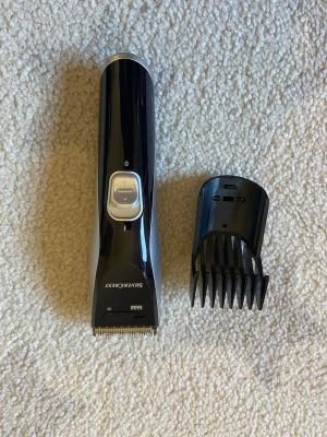 Svart hårtrimmer SilverCrest - Elektrisk hårtrimmer från SilverCrest i svart plast med silverfärgade detaljer. Medföljer en justerbar kam för olika längder. Perfekt för att fixa frisyren hemma. Ergonomisk design och tydliga knappar på framsidan.