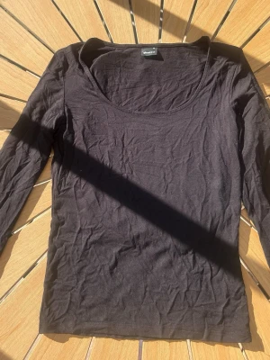 Svart långärmad topp från Gina - En enkel svart långärmad topp från Gina med rund halsringning och slits på ärmen. Passformen är normal och toppen har en klassisk, stilren look.🖤( lite nopprig)