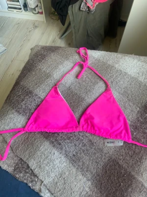 Rosa trekantsbikini från SHEIN - Säljer en snygg trekantsbikini från SHEIN i starkt rosa färg. Bikinin har tunna knytband i nacken och ryggen för justerbar passform. Perfekt för sommaren och strandhäng!