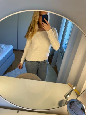 Vit ribbstickad tröja med båtringning - Säljer en stilren vit ribbstickad tröja med båtringning och långa ärmar. Tröjan har en smal passform och är perfekt att matcha med jeans. Materialet känns mjukt och stretchigt, vilket gör den bekväm att bära hela dagen. Använt typ 2 gånger 