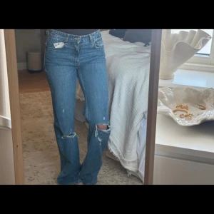 Blå slitna raka jeans med hål - Säljer ett par blå jeans med raka ben och slitningar på knäna. Storlek 34 och prislapp kvar💗 säljs då jag beställde i två olika storlekar💕jeansen säljs inte länge på hemsidan