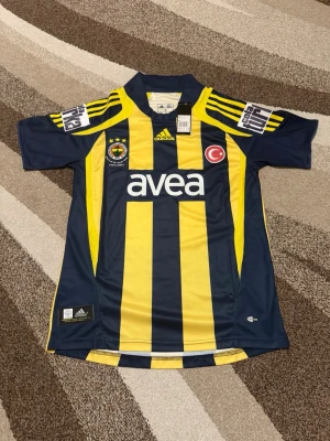 Fenerbahce 07-08 Hemmatröja  - Säljs av ICEKIT  Storlek: S Namn + nummer: Alex #10 Badge: Cola Turka Här kan du se tröjor i ICEKIT Outlet. Alla tröjor är helt nya och utan några problem. Du kan välja att köpa dem här eller direkt via vår hemsida.  Tröjorna finns tillgängliga hos ICEKIT på: https://www.icekit.se  Länk: https://www.icekit.se/collections/outlet