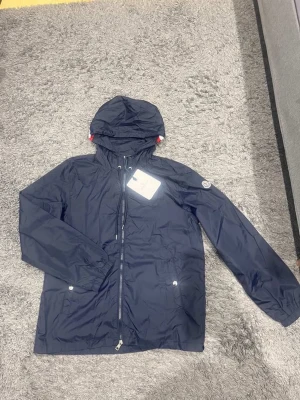 Moncler Windbreaker  - Helt ny och oanvänd marinblå Moncler Windbreaker, 10/10 skick. Det är storlek 3 vilket motsvarar L, men den passar även M. Den är tunn och passar perfekt nu inför våren och sommaren. Rekommenderar starkt!