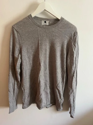 Grå stickad tröja från NN07 - En enkel och stilren grå långärmad stickad tröja från NN07. Klassisk passform och diskret design som funkar till det mesta.