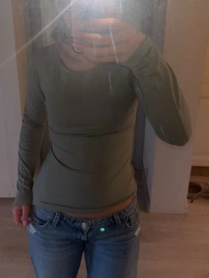 Grön långärmad topp från Kappahl - Snygg grön långärmad topp från Kappahl i stretchigt och mjukt material. Modellen är figurnära med rund halsringning och enkel design som passar till jeans eller kjol. Perfekt basplagg för din garderob💚Kolla in min profil för fler fina och trendiga plagg!