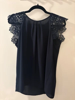 Blå blus med blommiga ärmar  - Tunn blå blus med fina blommärmar!