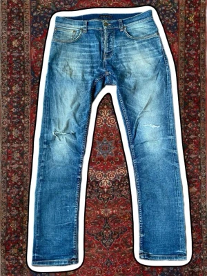  Nudie Jeans - Säljer ett par blå jeans från Nudie Jeans med slitningar . Skit snygga trendiga nudie jeans till ett grymt pris. Skriv om ni har frågor eller funderingar.