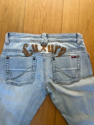 Ljusblå jeans med brodyr från ONLY - Snygga ljusblå jeans från ONLY med broderad text 'Luxury' i brunt på baksidan. Har tyvärr inga bilder med dom på då dom är för små för mig.  Stl 30/32. Innerbenslängden= 78cm. 
