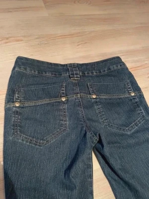 Low waist bootcut jeans med fickdetaljer  - Saljer dessa supersnygga jeans De har en jattefin wash färg i jeansen Utsvängda och låg midjade Snygga bakfickor Sitter väldigt flattering Tyvärr lite för sma för mig S midjemått 39cm innerbenslängd 81cm gren 21cm.      (Snygga mörkblå bootcut jeans med klassiska bakfickor och dekorativa sömmar. Jeansen har låg midja och utsvängda ben, perfekt för en avslappnad och trendig look. Tillverkade i denim med lätt stretch för extra komfort.) 