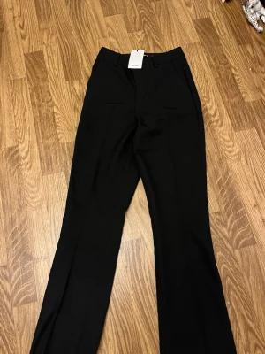 Svarta kostymbyxor från BikBok - Snygga svarta kostymbyxor från BikBok med raka ben . Klassisk design med fickor och hällor för skärp. Perfekta för en clean och stilren look. Materialet känns mjukt och har ett fint fall.