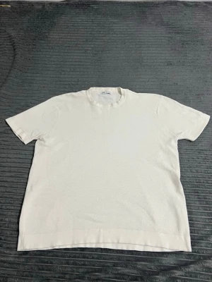 Vit strukturerad t-shirt från Zara - Säljer en vit t-shirt från Zara i storlek L. T-shirten har en strukturerad yta med diskret mönster, rund halsringning och korta ärmar. Perfekt för dig som gillar stilrena och enkla plagg med lite extra känsla i materialet.