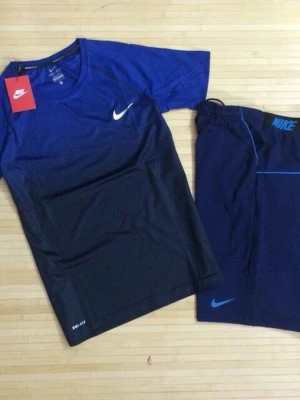 Nike träningsset blå och svart - Nike träningsset med t-shirt och shorts. T-shirten är blå upptill och svart nedtill med vit Nike-logga och Dri-FIT-material. Shortsen är mörkblå med blå detaljer och Nike-logga. Perfekt för träning och sport.