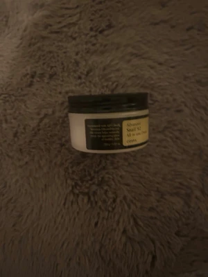 COSRX Advanced Snail 92 All in One Cream - En burk med COSRX Advanced Snail 92 All in One Cream, en populär koreansk ansiktskräm med snigelsekret. Krämen är vit med svart lock och har en lätt gel-liknande konsistens som återfuktar huden på djupet.