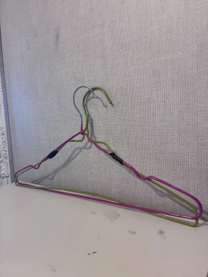 2st färggalgar i metall grön & rosa - 2st galgar gjord av böjd metalltråd i grönt och rosa. Perfekt för att hänga kläder eller som dekoration i garderoben. Säljs som ett set.