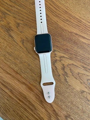 Smartklocka med rosa silikonband - Säljer en Apple Watch SE 40mm gold Alu pink sand. En rosé färgad Apple Watch som inte använts på ca 1 år. Den har inga repor, sprickor eller skador. Har senaste uppdateringarna och funkar exakt som den ska. Jag har kvar lådan till klockan samt laddare. Har även 5 band som man kan byta och justera hur man vill för att matcha med olika outfits. Har även kvar orginal banden som kommer med klockan. Batteri hälsan ligger på 96%. Den fungerar alltså precis som en helt ny då jag sköt om den bra. 