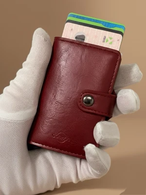 Vinröd plånbok i läder från - Svensk märke  - Snygg vinröd plånbok från Cosmos Sweden i rikigt stark PU läder med knappstängning. Plånboken har ett stilrent och kompakt format med plats för flera kort och ett metallhölje som skyddar innehållet. Perfekt för dig som vill ha en modern och smidig accessoar. Får även plats med sedlar. RFID skydda. Snabb leverans 🚚💨