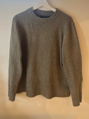 Grå stickad tröja från Amisu - Mysig grå stickad tröja från Amisu med rund halsringning och ribbade muddar vid ärmslut och nederkant. Perfekt för lager-på-lager och enkel att matcha med jeans eller kjol. Klassisk och stilren design som funkar året runt.