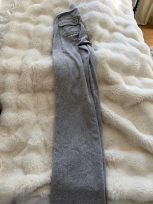 Grå mjukisbyxor från Juicy Couture - Säljer ett par grå mjukisbyxor från Juicy Couture i storlek XS. Byxorna har en klassisk rak passform.💕 Den har tappat en metall grej från snöret (se bilden) men är annars i bra skick