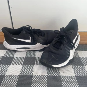 Svarta Nike sneakers - Snygga svarta Nike sneakers med vit sula och vit swoosh på sidan. Skorna har en sportig design med mesh-överdel för bra ventilation och klassisk snörning. Perfekta för dig som gillar en clean och stilren look till vardagsoutfiten.